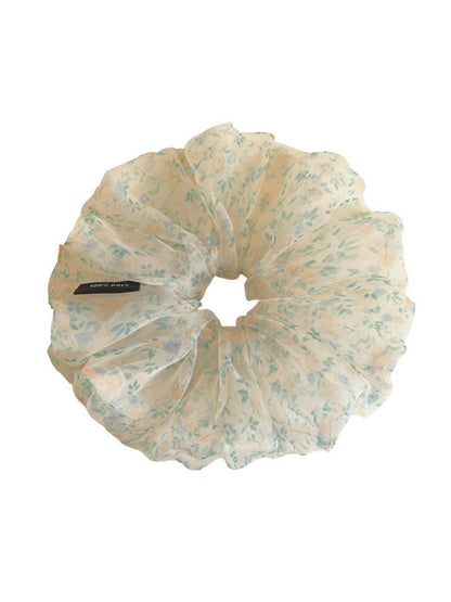 Green tulle scrunchie with small white and pink flowers displayed on a white background