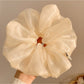 Gifty minimalist shiny scrunchie worn in a ponytail on dark hair