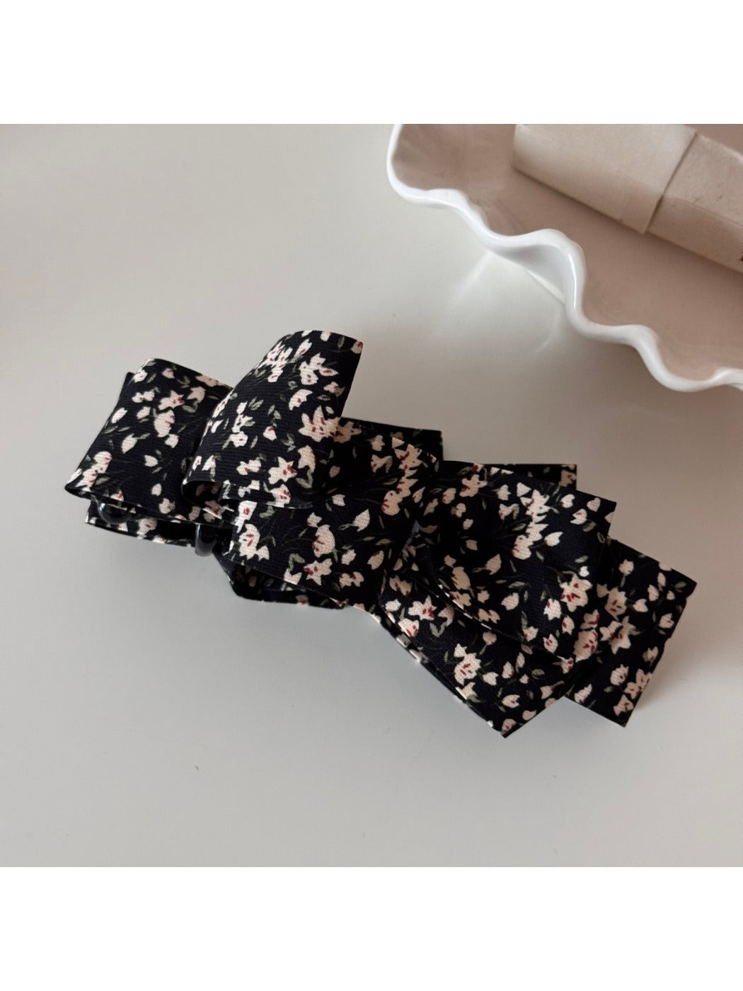 Beau small floral print bow hair clip held in hand showing size and detail