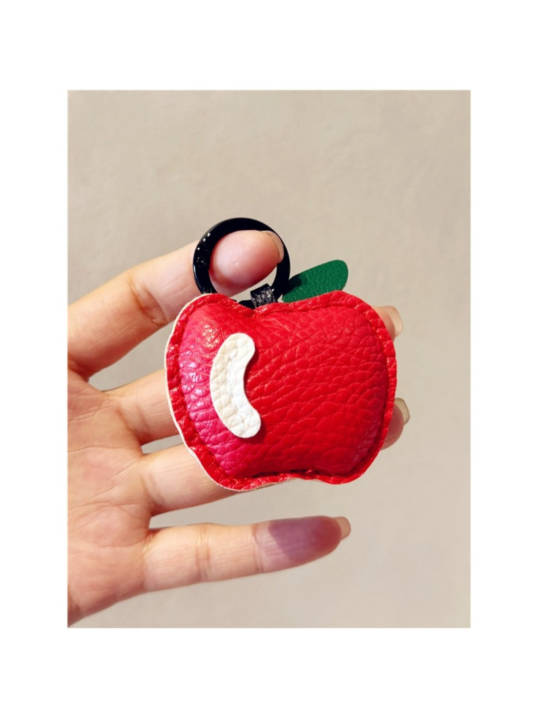 Apple keychain hanging from a backpack zipper pull in natural light