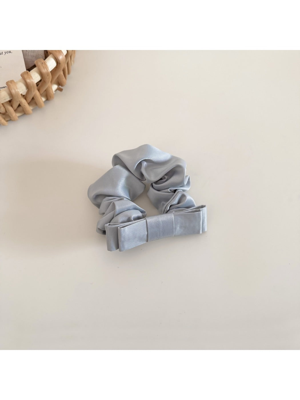 Side angle of the satin bow scrunchie highlighting the bow's shape and fabric sheen