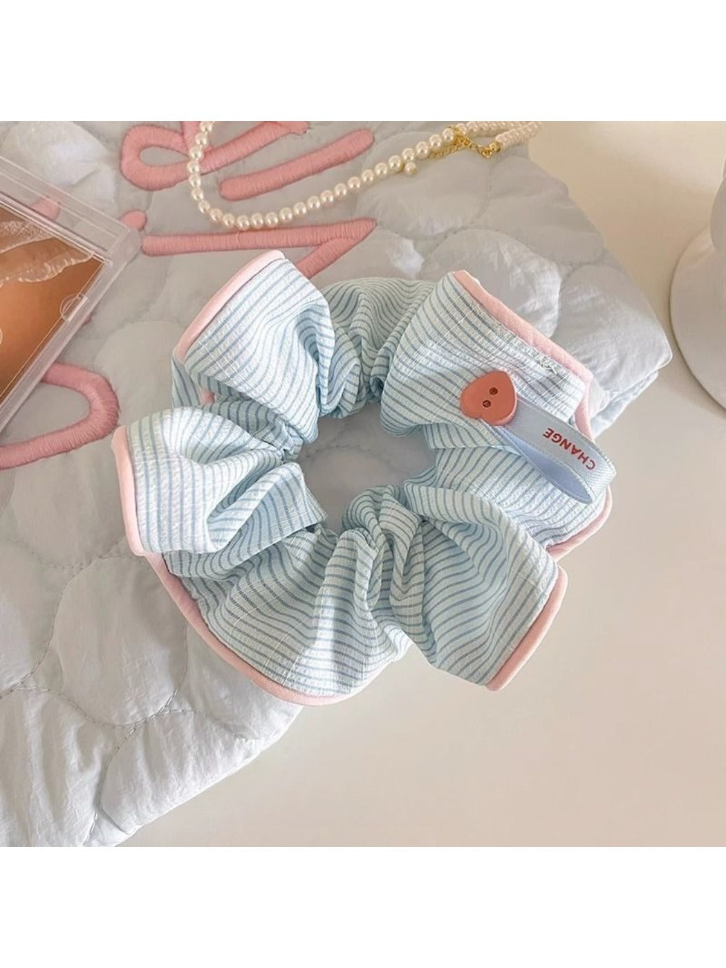 Gifty scrunchie in soft fabric with subtle stripes, shown from side angle