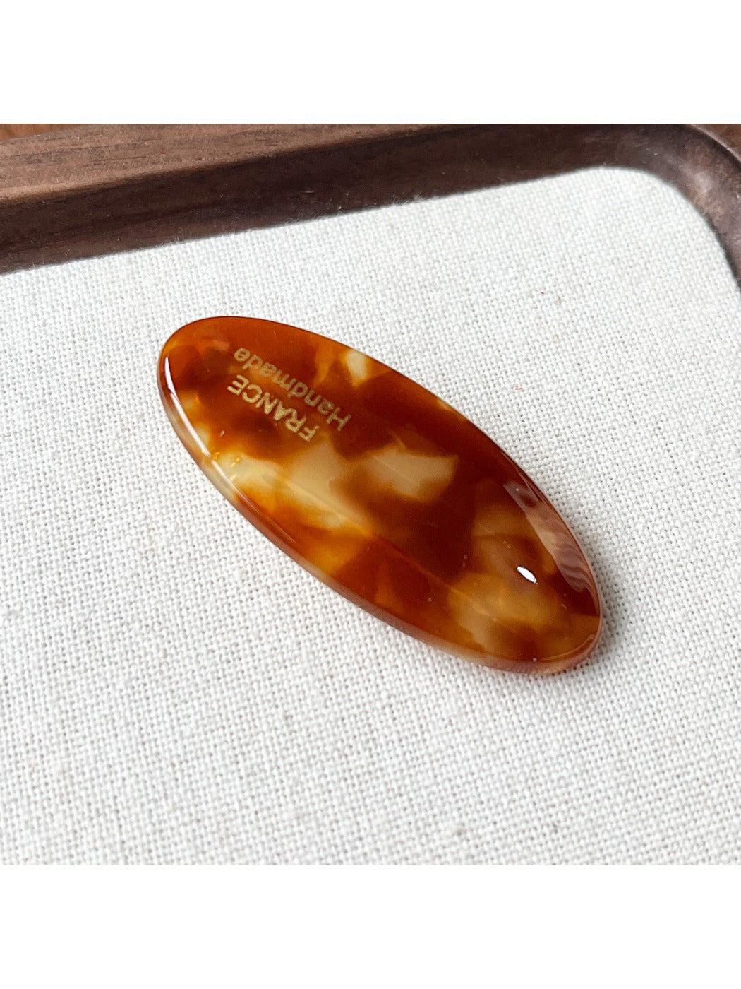 Beau Sweet Oval Acetate Hair Clip with light reflecting off its smooth surface