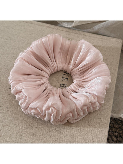 Satin scrunchie with ruched design placed flat to show full shape