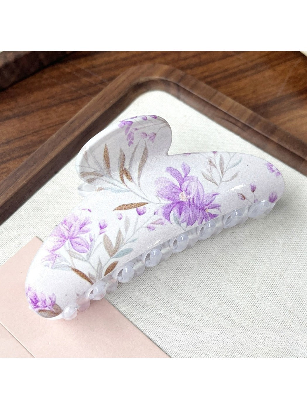Beau hair clip held in hand showing size and colorful floral design