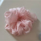 Gifty scrunchie paired with matching pastel accessories on a wooden table