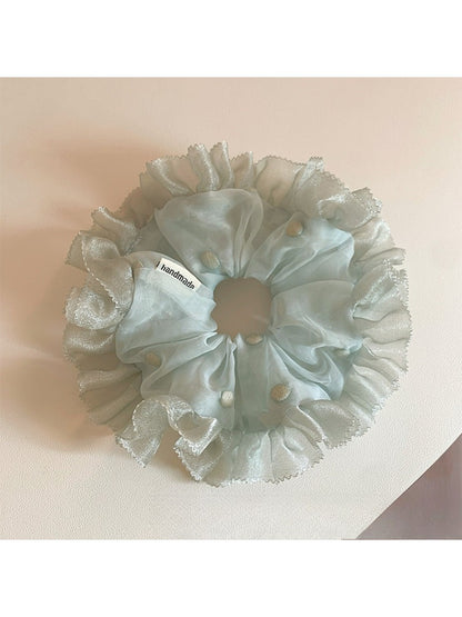 Gifty black tulle scrunchie with white polka dots styled on a wooden surface