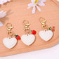 Heart shaped bag charm keychain in red leather with gold hardware on white background
