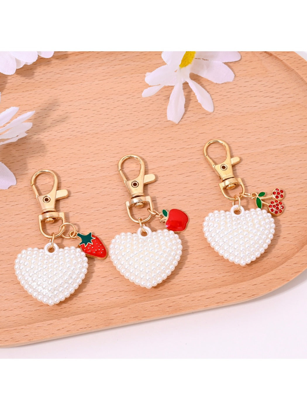 Heart shaped bag charm keychain in red leather with gold hardware on white background