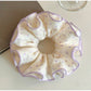 Purple polka dot scrunchie wrapped around a ponytail on a model