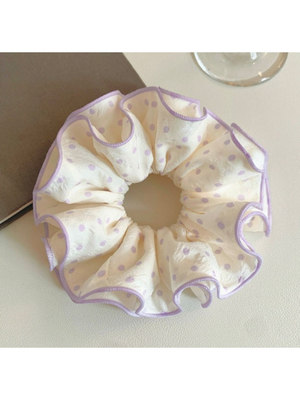 Purple polka dot scrunchie wrapped around a ponytail on a model