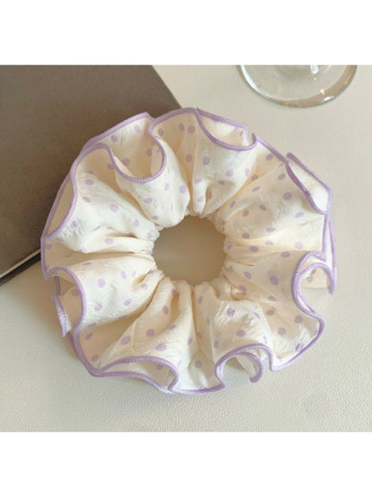 Purple polka dot scrunchie wrapped around a ponytail on a model