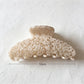 Beau tiny floral acetate claw clip held in hand showing size and design