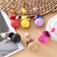 Close-up of Earedge fabric flower raffia ball earrings on white background
