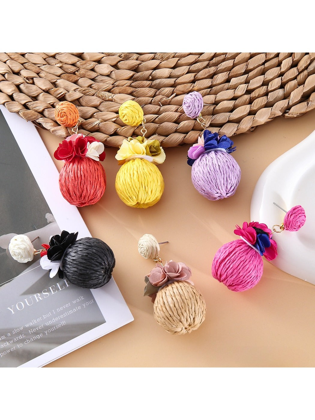 Close-up of Earedge fabric flower raffia ball earrings on white background
