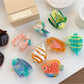 Beau fish claw clip held in hand displaying size and colorful pattern