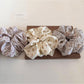 Gifty floral scrunchie wrapped around a ponytail on dark hair