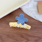 Beau flower shaped claw clip held in hand showing size and shape