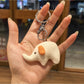 Elephant charm keychain hanging from a metal hook on a display rack