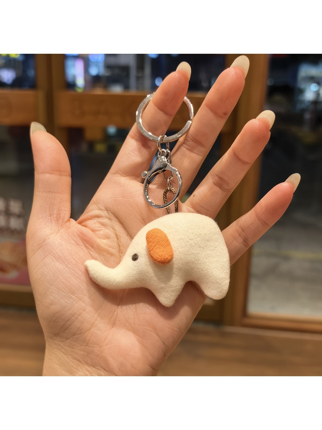 Elephant charm keychain hanging from a metal hook on a display rack