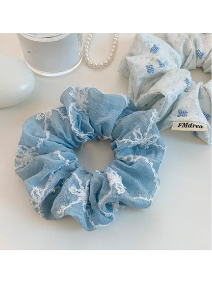 Blue scrunchie with white bows wrapped around a wrist