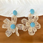 Top view of raffia flower shaped drop earrings highlighting natural texture