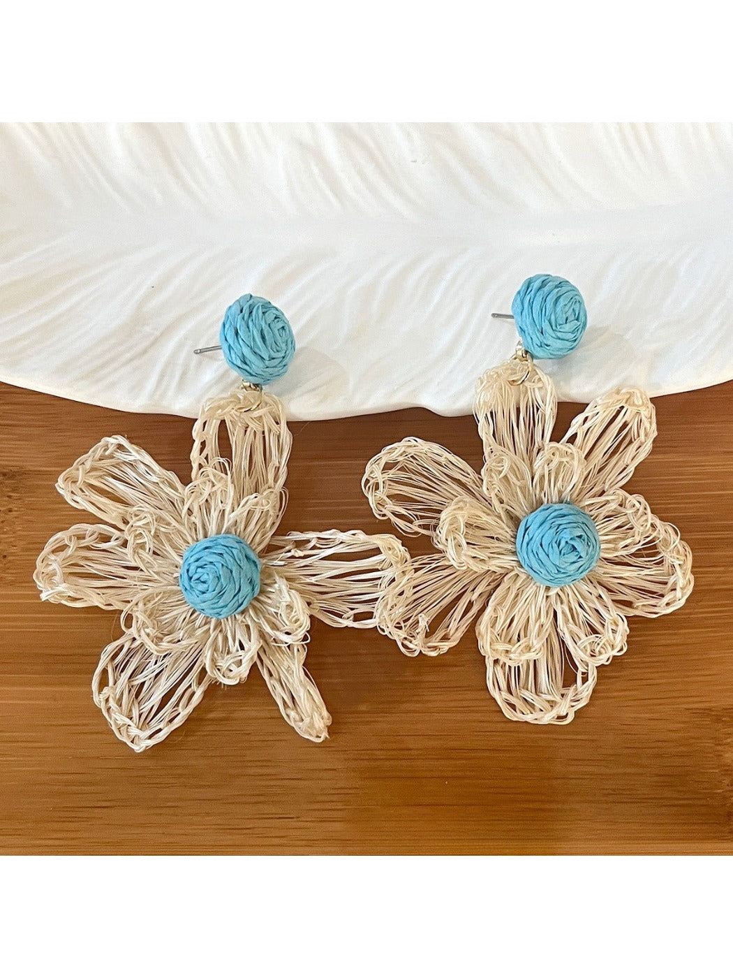 Top view of raffia flower shaped drop earrings highlighting natural texture