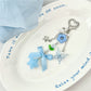 Blue flower bow keychain hanging from a bag zipper pull