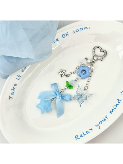 Blue flower bow keychain hanging from a bag zipper pull