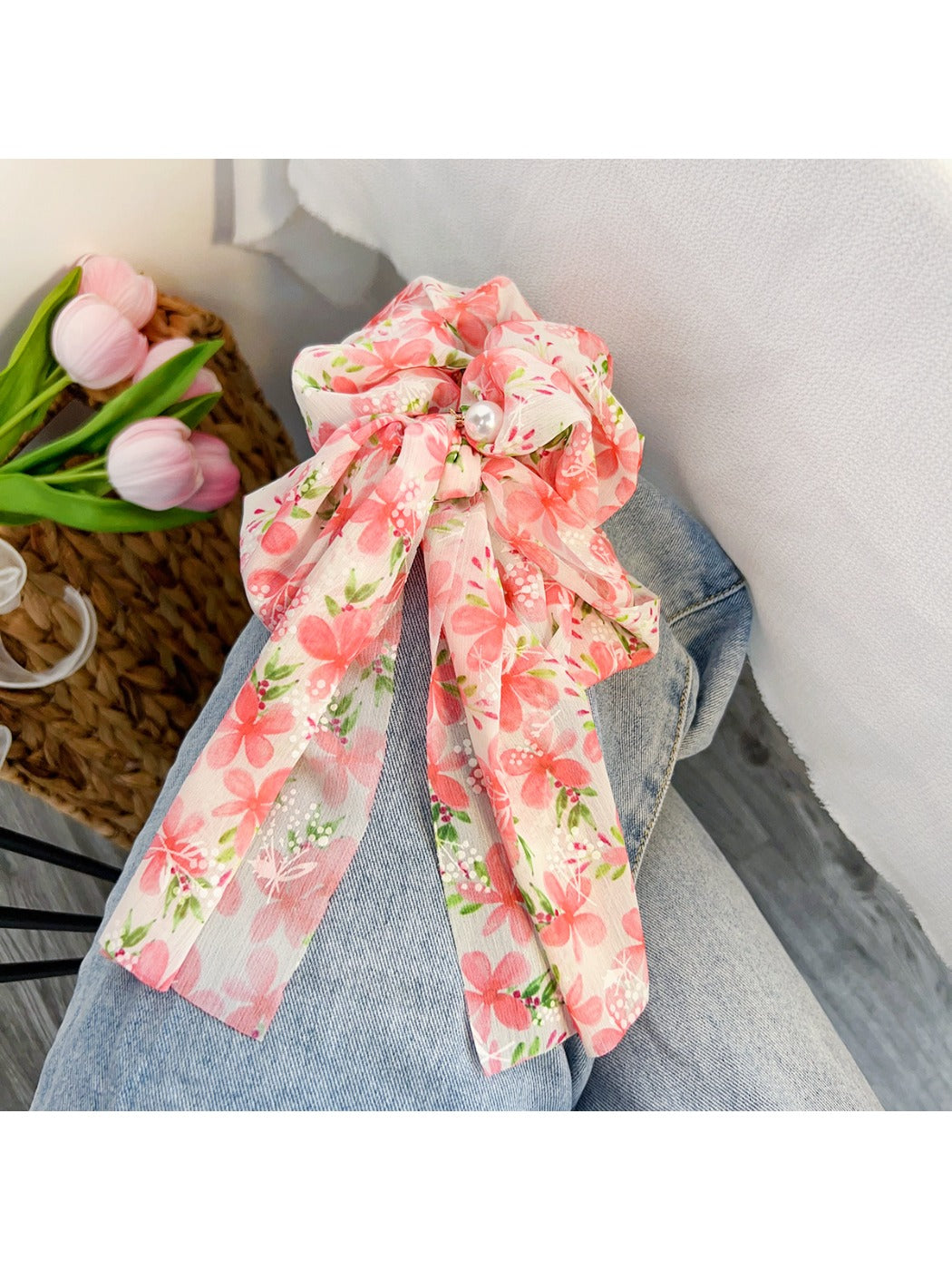 Red floral print bow scrunchie held in hand against neutral background
