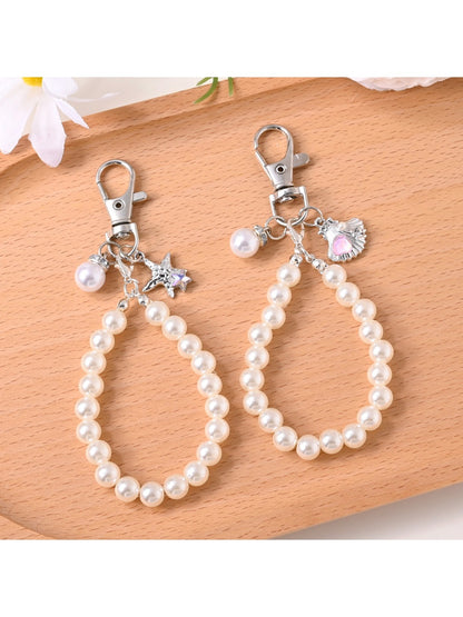 Keypus beaded bag charm keychain hanging from a beige handbag strap