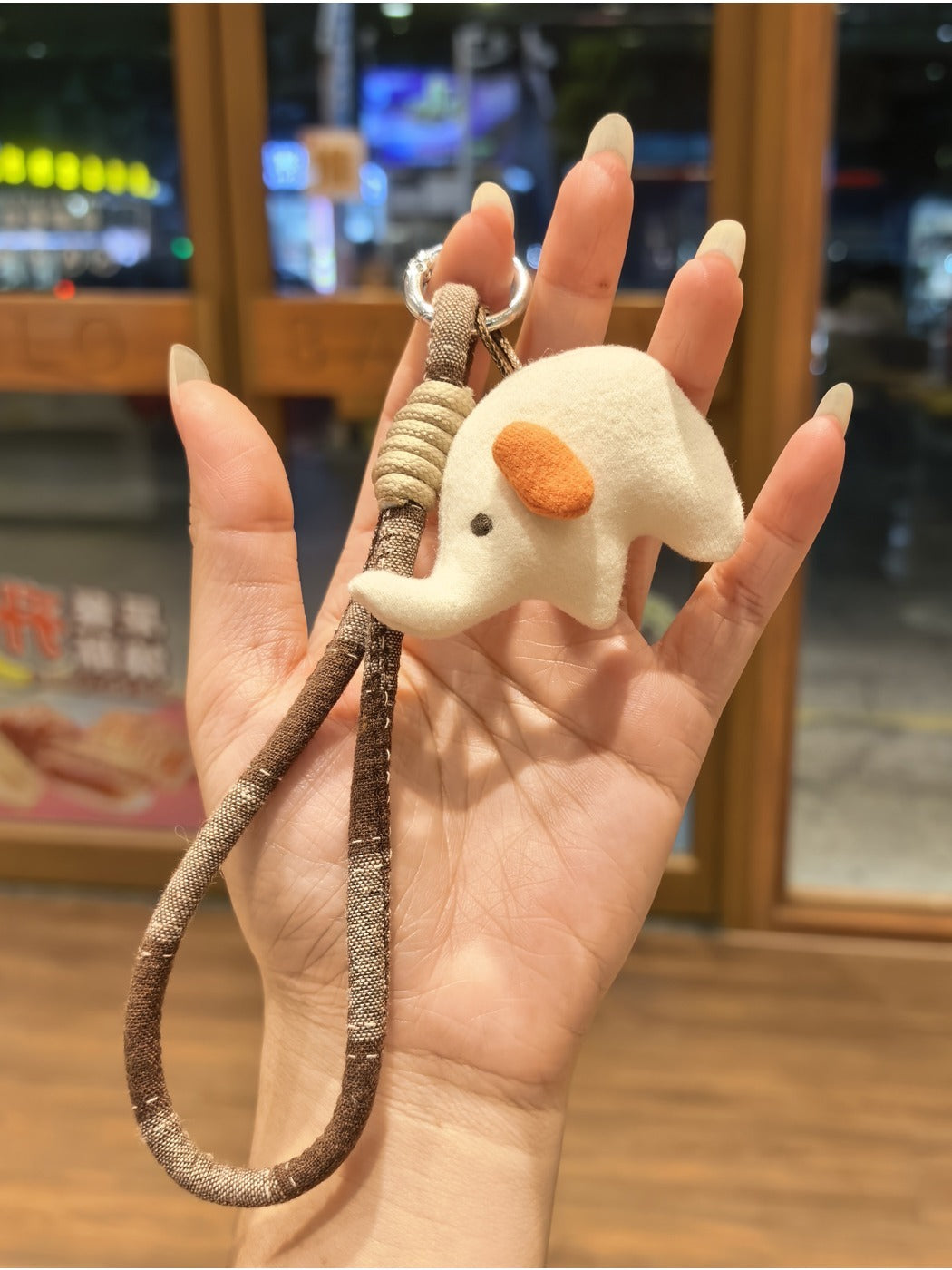 Elephant charm keychain hanging from a set of keys on a wooden surface