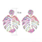 Pair of raffia woven hollow leaf shaped earrings displayed on a flat surface