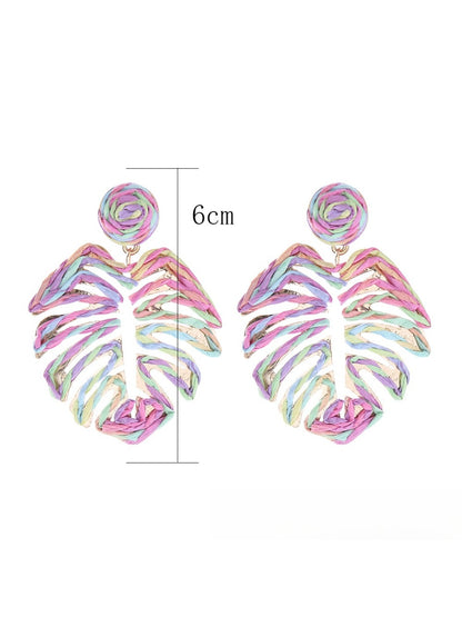 Pair of raffia woven hollow leaf shaped earrings displayed on a flat surface