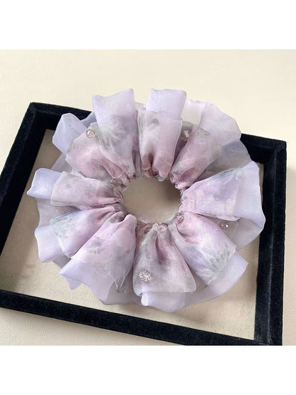 Purple scrunchie wrapped around a ponytail on a model with dark hair