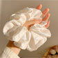 Satin scrunchie with minimalist bow pattern displayed on a hand