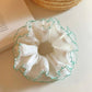 Close-up of white tulle fabric and green trim on double scrunchie