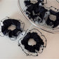 Black scrunchie with polka dot trim styled on a model's wrist