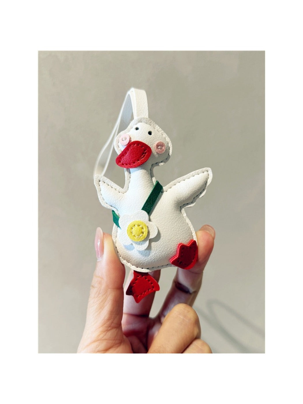 Yellow duck keychain held in a hand to show size and scale
