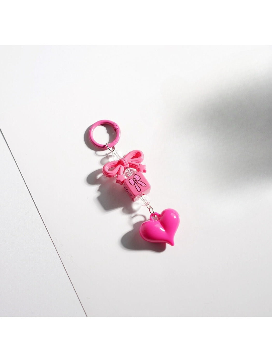 Keypus keychain displayed on a wooden surface showing pink bow and heart beads