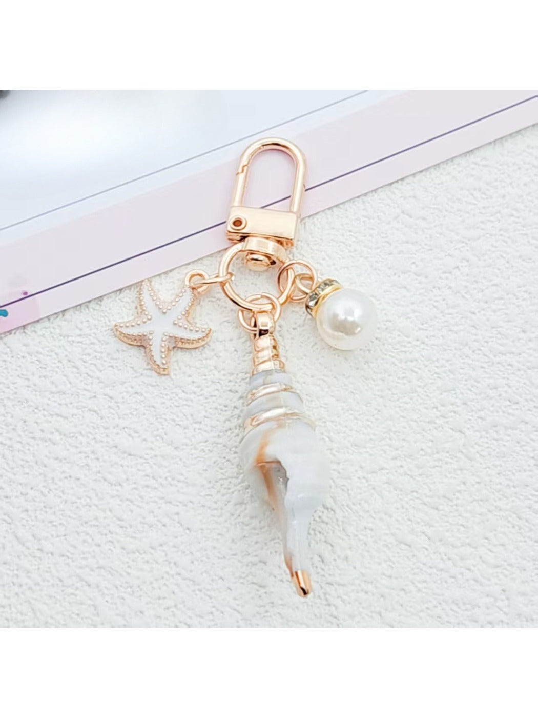 Gold conch keychain hanging from a leather bag strap