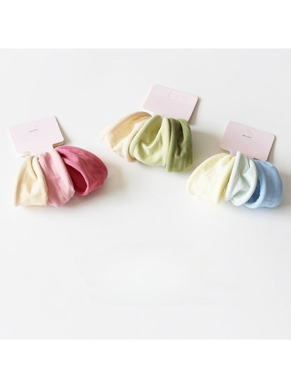 Multiple solid color hair ties stacked together displaying various muted tones