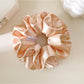 Flat lay of multiple Gifty satin double layer scrunchies in various colors arranged in a circle