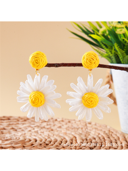 Bohemian daisy floral raffia stud earrings displayed in natural outdoor setting