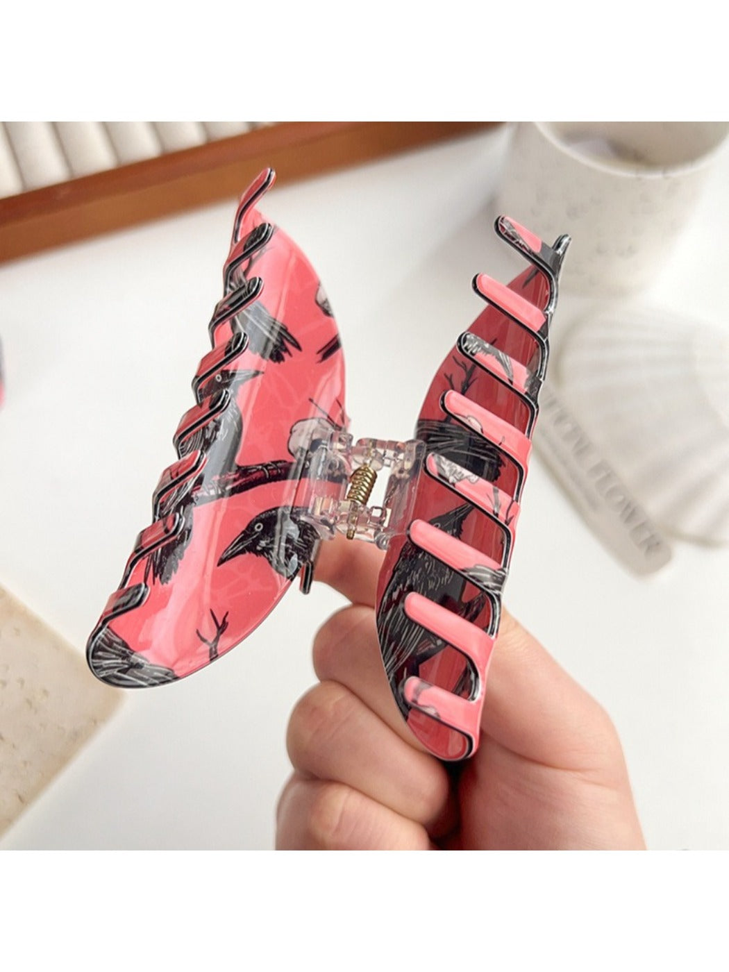 Beau hair claw clip held in hand displaying size and crow motif