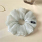 Grey scrunchie wrapped around a ponytail on a model with light hair