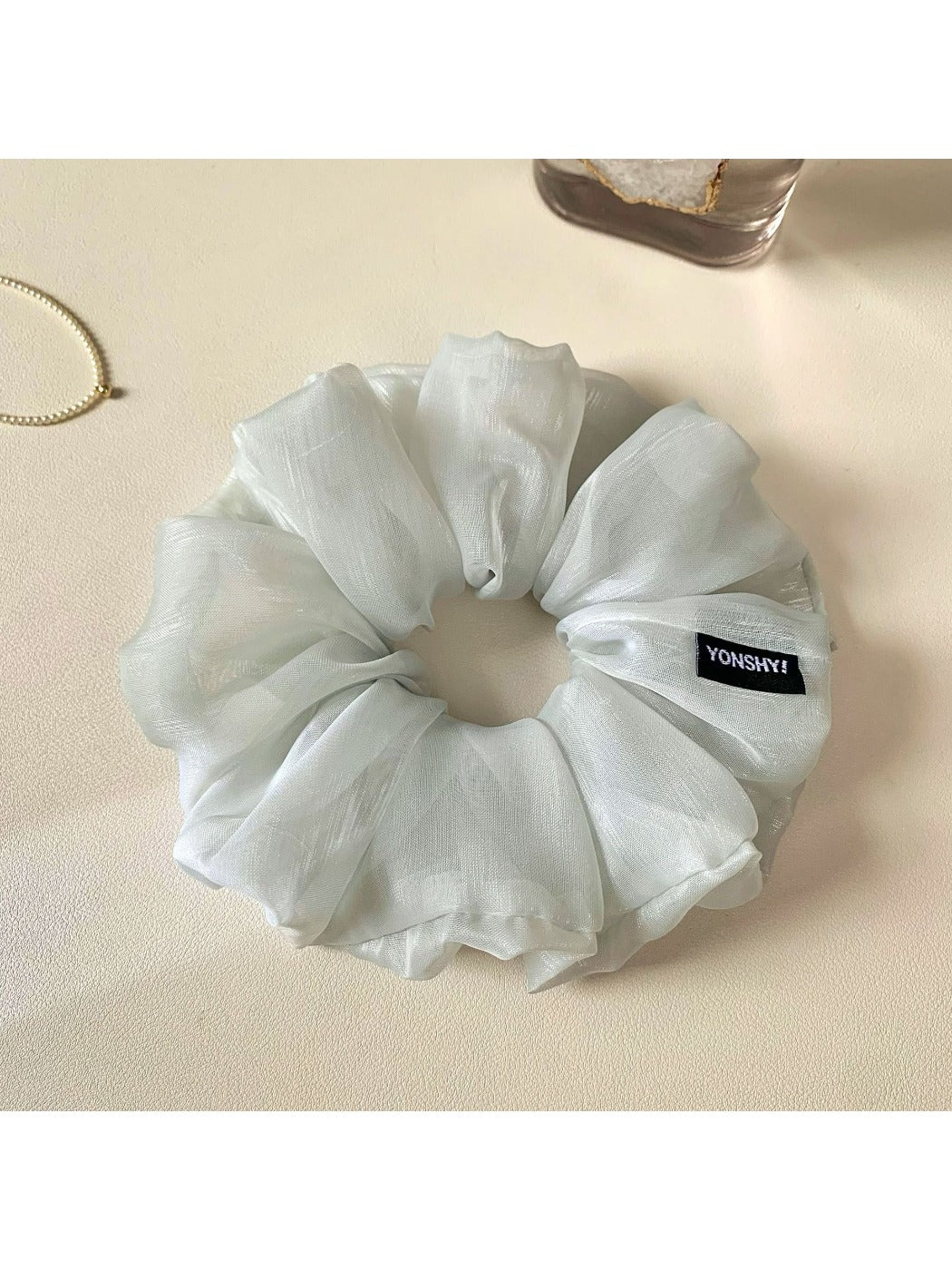 Grey scrunchie wrapped around a ponytail on a model with light hair