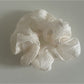 Beige sheer tulle scrunchie displayed flat on a white surface
