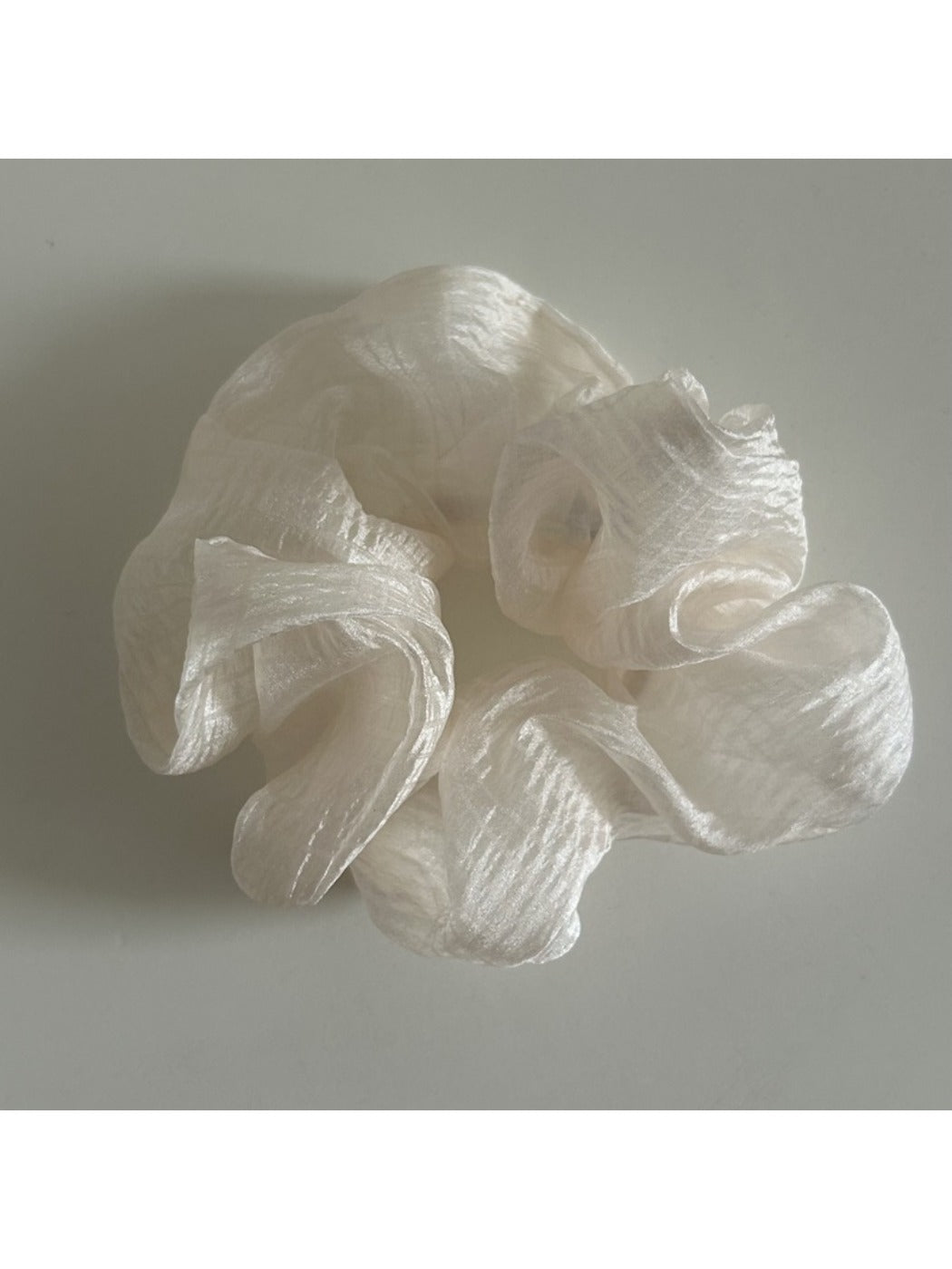 Beige sheer tulle scrunchie displayed flat on a white surface
