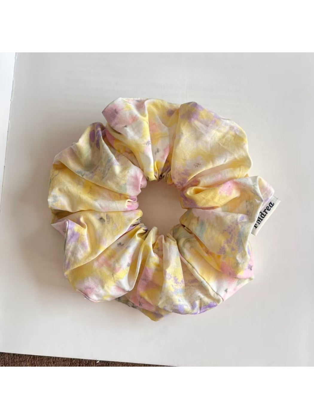 Close-up of vibrant, multicolored scrunchie showing detailed brushstroke design